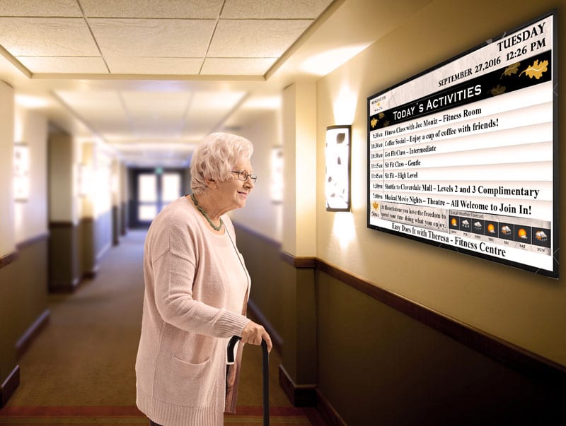 senior looking at digital sign at retirement home hallway