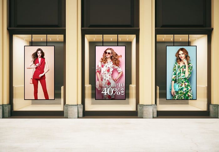 three portrait mode digital storefront displays showing promotions