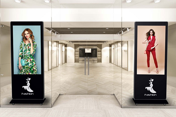 two digital kiosks behind storefront window showing fashion models