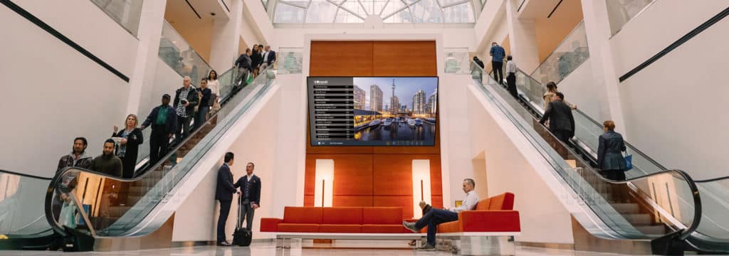 Digital lobby signage above a sitting area in an office buillding